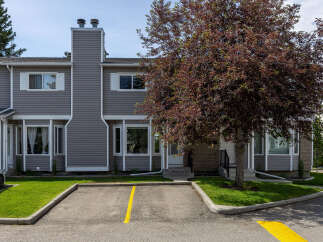Discover comfortable living in this charming townhouse featuring a modern grey siding exterior and a prominent brick entrance.