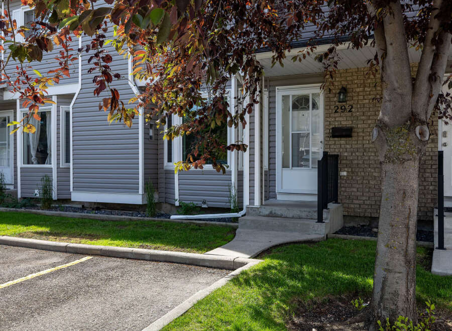 Discover this charming townhouse featuring a welcoming entrance with a paved walkway and steps leading to the front door.