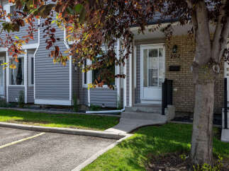 Discover this charming townhouse featuring a welcoming entrance with a paved walkway and steps leading to the front door.