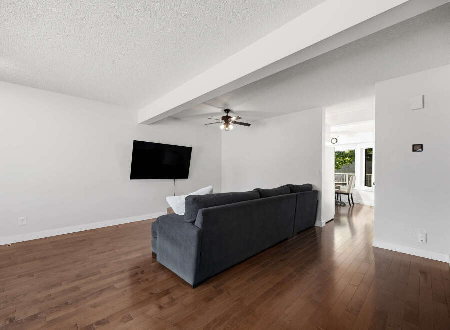 Experience modern living in this spacious living room featuring a sleek dark gray sectional sofa and a wall-mounted flat-screen TV.