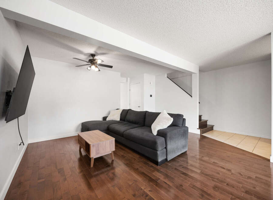 Experience modern living in this spacious living room featuring a sleek dark gray sectional sofa and a stylish wooden coffee table.