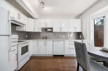 This modern kitchen features sleek white cabinetry and a stylish gray subway tile backsplash.