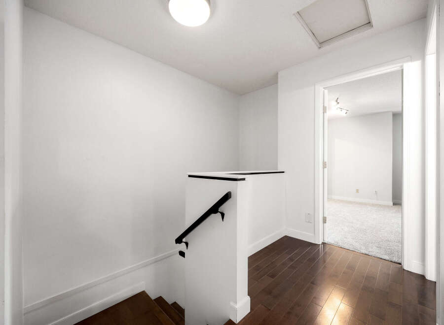 Ascend to the upper level of this home via a beautifully crafted staircase with rich hardwood flooring and a sleek black handrail.