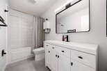 This modern bathroom features a sleek white vanity with black hardware, complemented by a large black-framed mirror and a stylish black faucet.