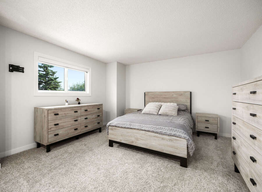 This bright and airy bedroom features a comfortable queen-size bed with a stylish patterned comforter and two plush throw pillows.