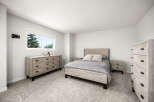 This bright and airy bedroom features a comfortable queen-size bed with a stylish patterned comforter and two plush throw pillows.
