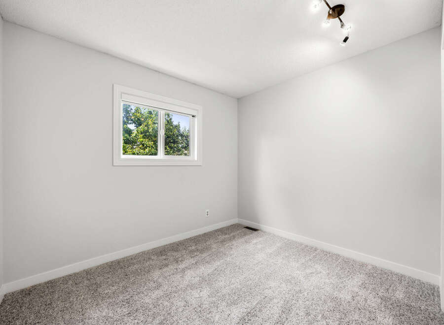 This bright and airy bedroom features a large window that floods the space with natural light, offering a view of lush greenery.