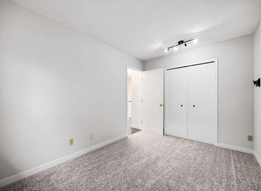 This spacious bedroom features plush carpeting and ample closet space, perfect for comfortable living.