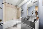 This modern bathroom features a sleek stainless steel sink and vanity, complemented by a large mirror and a stylish faucet.