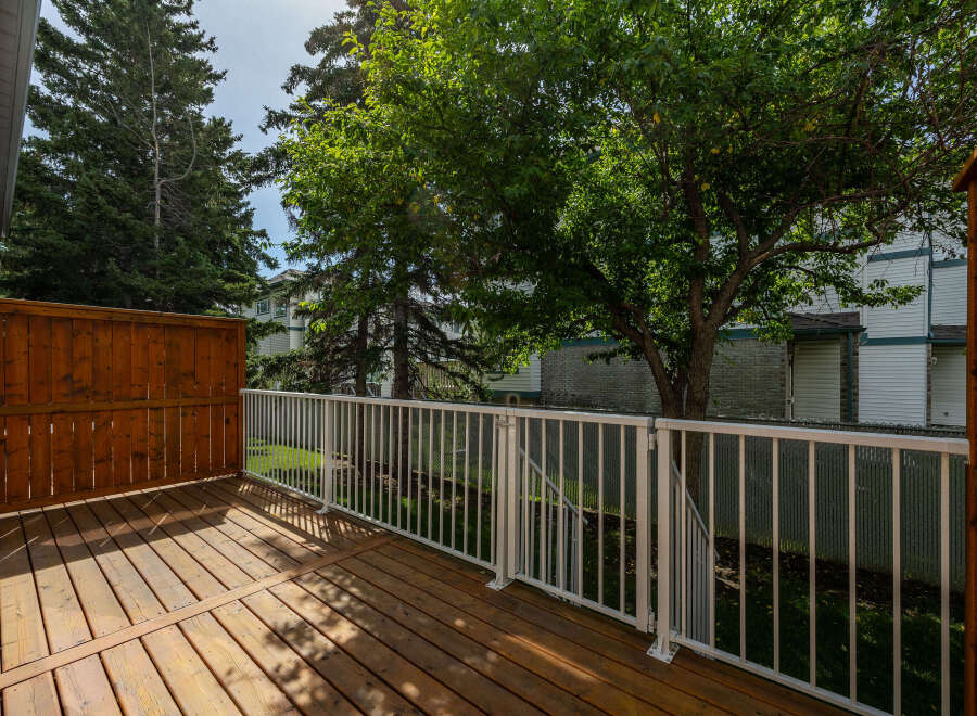 Enjoy outdoor living on this spacious wooden deck, complete with a white railing for safety and style.