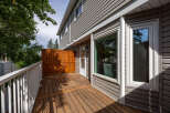 Enjoy outdoor living on this spacious wooden deck, complete with a white railing and a privacy screen.