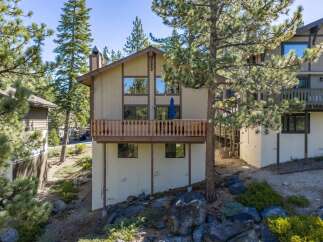 Nestled amidst tall pine trees, this charming mountain home offers a serene retreat with its multi-level design and spacious wooden deck perfect for enjoying the crisp alpine air.