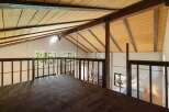 Experience the unique charm of this loft space, featuring a vaulted wood-paneled ceiling with exposed beams that create a warm, rustic ambiance.