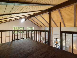 Experience the unique charm of this loft space, featuring a vaulted wood-paneled ceiling with exposed beams that create a warm, rustic ambiance.