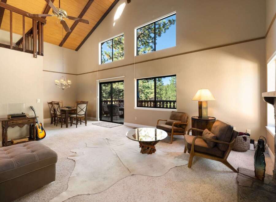 Experience the grandeur of this spacious living room, featuring a soaring vaulted ceiling with exposed wood beams and a striking stone fireplace.