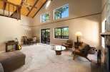 Experience the grandeur of this spacious living room, featuring a soaring vaulted ceiling with exposed wood beams and a striking stone fireplace.