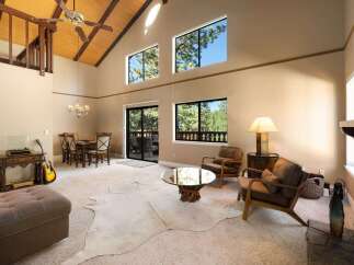 Experience the grandeur of this spacious living room, featuring a soaring vaulted ceiling with exposed wood beams and a striking stone fireplace.