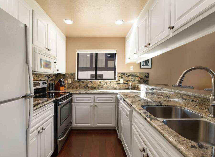 Discover this charming kitchen featuring pristine white cabinetry and elegant granite countertops.