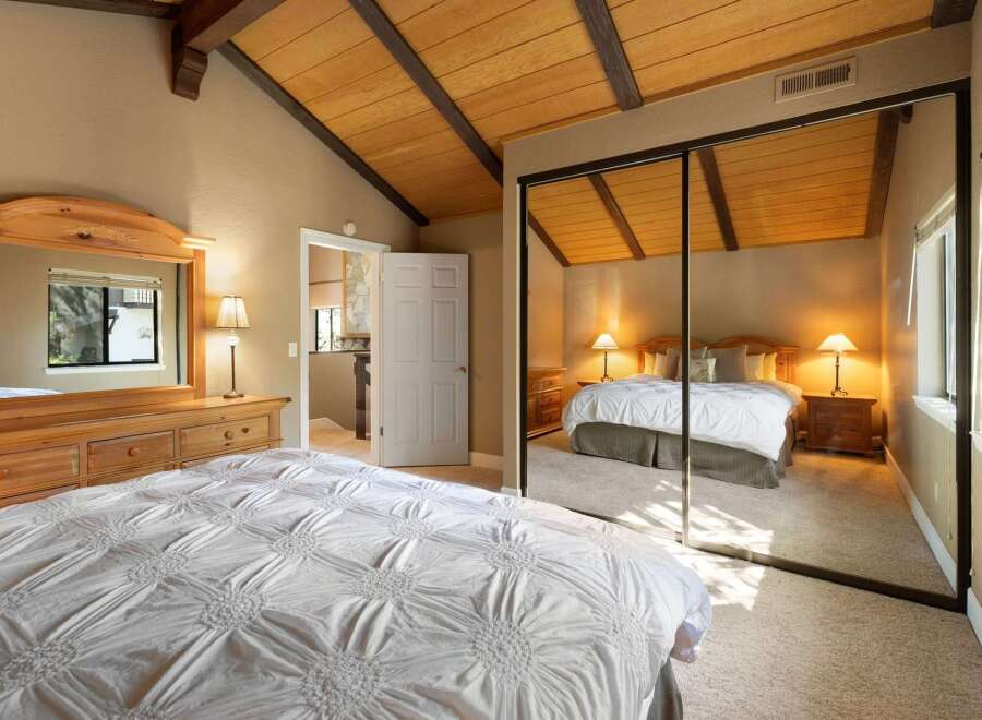 Experience ultimate comfort in this spacious bedroom, featuring a vaulted wood-beam ceiling and a large mirrored closet.