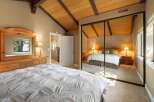 Experience ultimate comfort in this spacious bedroom, featuring a vaulted wood-beam ceiling and a large mirrored closet.