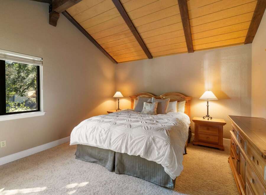 Experience cozy comfort in this charming bedroom, featuring a plush white comforter and a rustic wooden headboard.