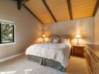 Experience cozy comfort in this charming bedroom, featuring a plush white comforter and a rustic wooden headboard.