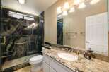 Experience luxury in this stunning bathroom featuring a spacious walk-in shower with intricate granite tile and a convenient built-in bench.