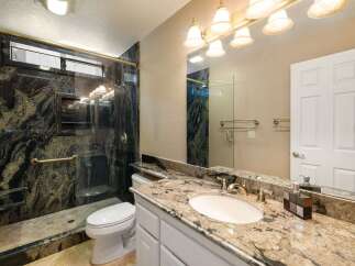 Experience luxury in this stunning bathroom featuring a spacious walk-in shower with intricate granite tile and a convenient built-in bench.