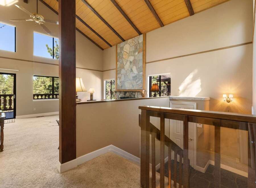 Experience breathtaking views from this stunning home featuring a dramatic vaulted ceiling with exposed wood beams and a striking stone fireplace.