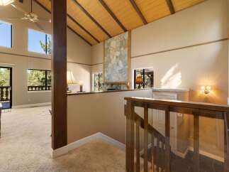 Experience breathtaking views from this stunning home featuring a dramatic vaulted ceiling with exposed wood beams and a striking stone fireplace.