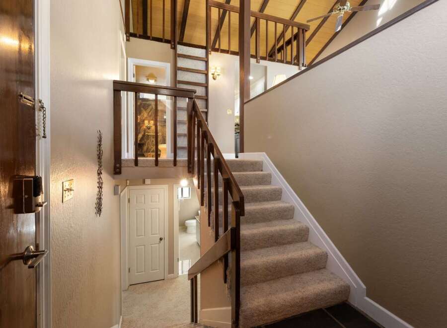Step into this charming home featuring a welcoming entryway with a wooden door and a convenient staircase leading to the upper level.