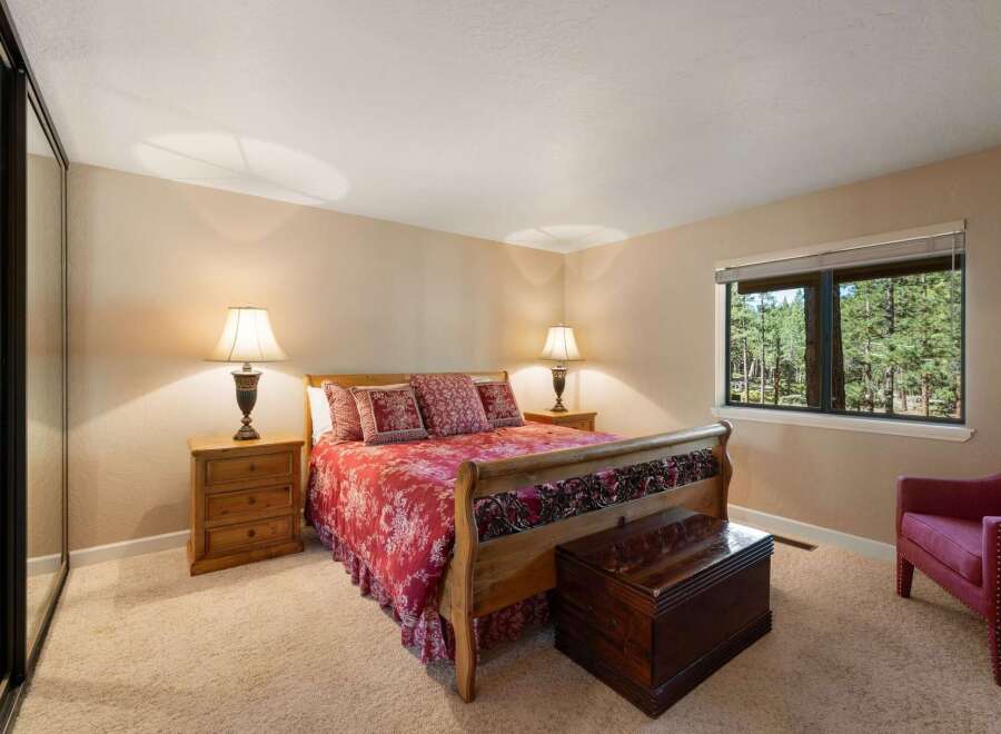 Experience ultimate comfort in this inviting bedroom, featuring a luxurious sleigh bed adorned with a vibrant red floral comforter and matching pillows.
