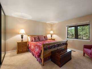 Experience ultimate comfort in this inviting bedroom, featuring a luxurious sleigh bed adorned with a vibrant red floral comforter and matching pillows.