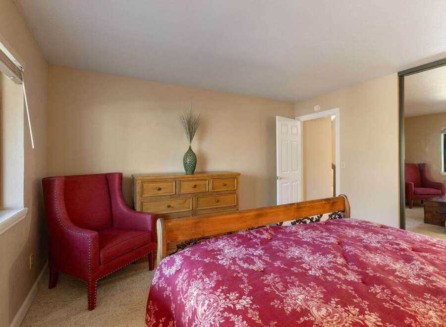 This charming bedroom features a comfortable queen-size bed with a striking red floral comforter, perfect for a restful night's sleep.