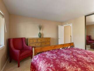 This charming bedroom features a comfortable queen-size bed with a striking red floral comforter, perfect for a restful night's sleep.