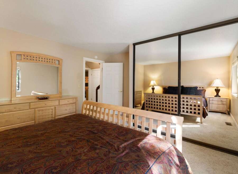 This spacious bedroom features a large wooden dresser with an attached mirror, perfect for storing your belongings and getting ready.