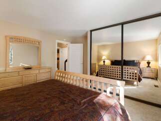 This spacious bedroom features a large wooden dresser with an attached mirror, perfect for storing your belongings and getting ready.