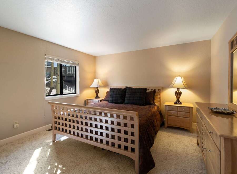 This charming bedroom features a light wood sleigh bed with a striking lattice design, complemented by a rich brown comforter and plaid accent pillows.