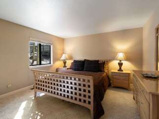This charming bedroom features a light wood sleigh bed with a striking lattice design, complemented by a rich brown comforter and plaid accent pillows.