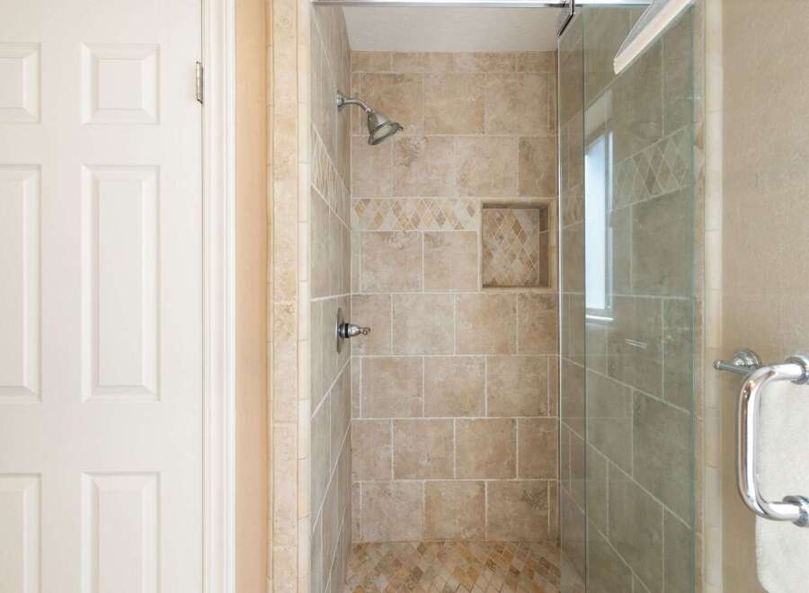 Step into this beautifully appointed bathroom featuring a spacious walk-in shower with elegant tiled walls and a convenient built-in niche.