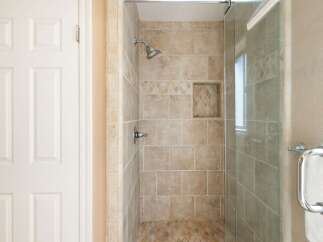 Step into this beautifully appointed bathroom featuring a spacious walk-in shower with elegant tiled walls and a convenient built-in niche.