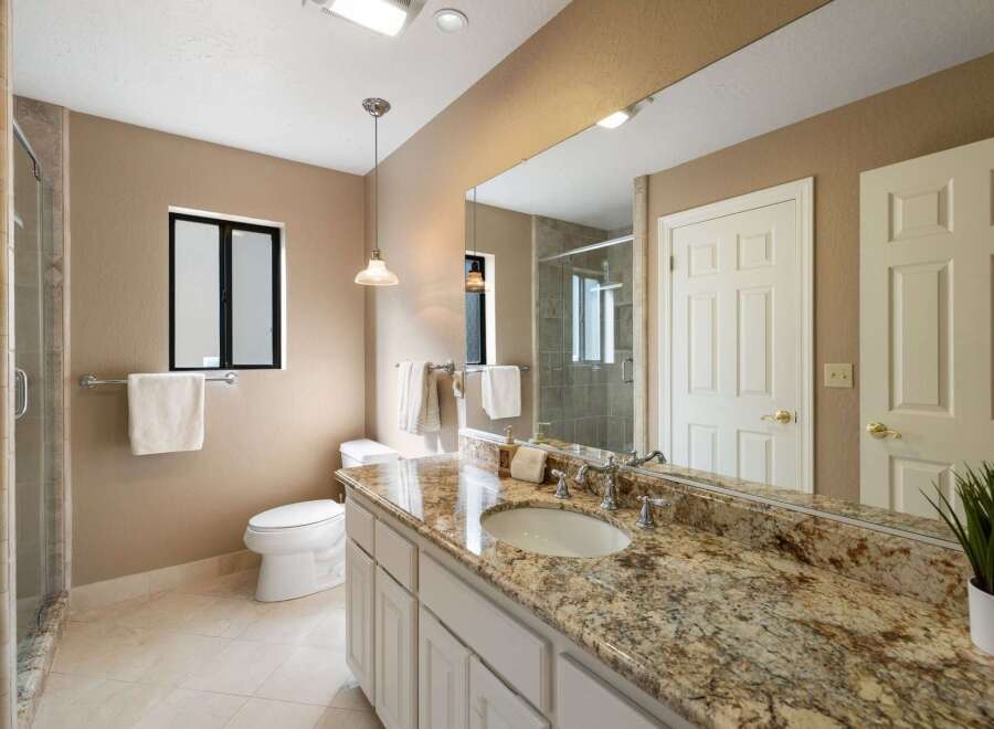 This luxurious bathroom features a spacious vanity with a granite countertop and an undermount sink, complemented by elegant chrome fixtures.