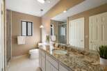 This luxurious bathroom features a spacious vanity with a granite countertop and an undermount sink, complemented by elegant chrome fixtures.