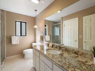 This luxurious bathroom features a spacious vanity with a granite countertop and an undermount sink, complemented by elegant chrome fixtures.