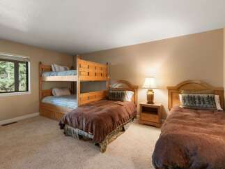 This charming bedroom offers comfortable sleeping arrangements with a sturdy wooden bunk bed and a separate twin bed, perfect for families or groups.