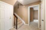 Step into this inviting home featuring a bright entryway with a white door and a carpeted staircase leading upstairs.