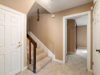 Step into this inviting home featuring a bright entryway with a white door and a carpeted staircase leading upstairs.