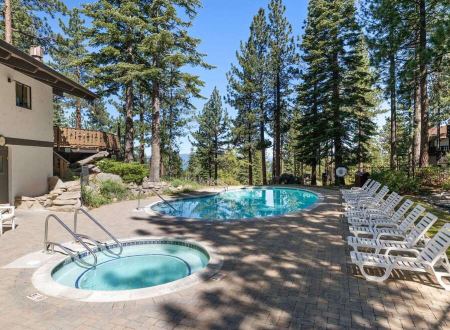 Enjoy a refreshing dip in this stunning outdoor pool and hot tub area, surrounded by towering pine trees and offering breathtaking views.