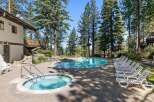 Enjoy a refreshing dip in this stunning outdoor pool and hot tub area, surrounded by towering pine trees and offering breathtaking views.