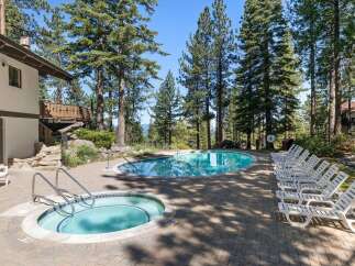 Enjoy a refreshing dip in this stunning outdoor pool and hot tub area, surrounded by towering pine trees and offering breathtaking views.